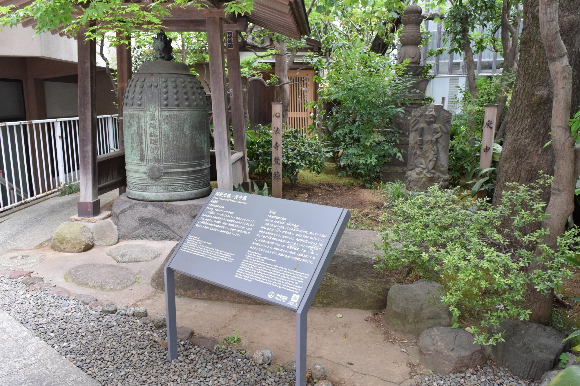 境内内の梵鐘とその横に設置された銅製梵鐘/庚申塔の説明板の写真