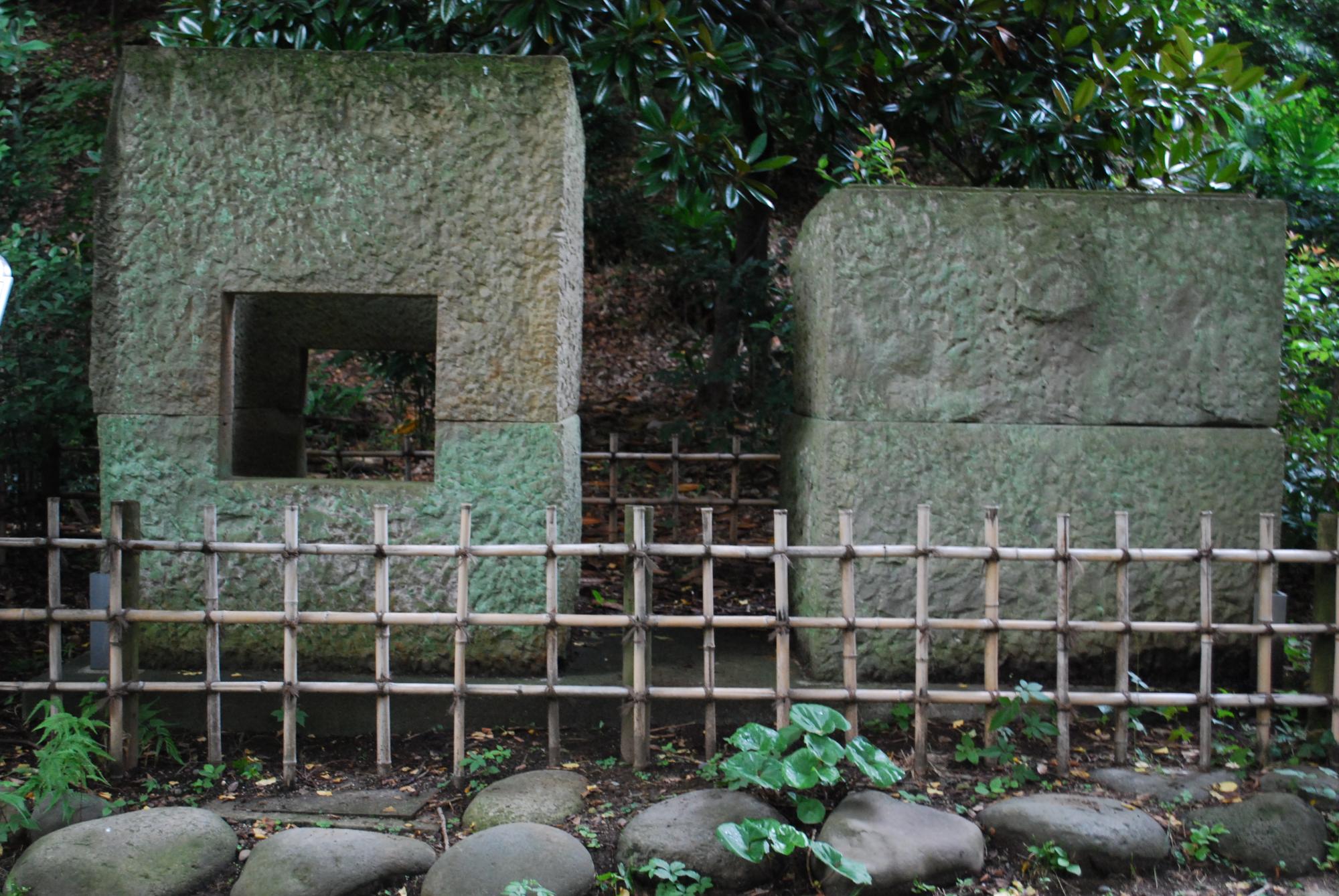 柵の中に大きな四角の石が2つ並び、左側の石は中央が四角の穴があいている石枡の写真