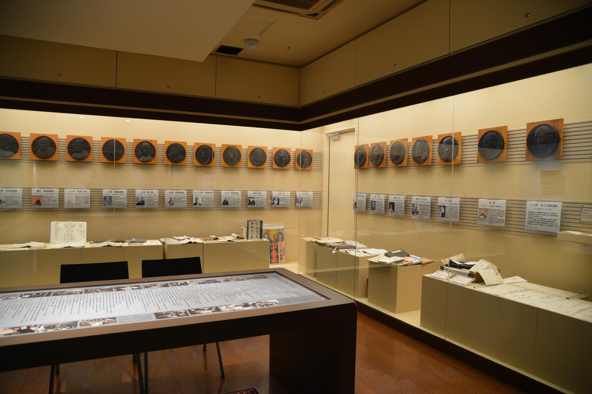 ガラス張りの展示室の中にたくさんの資料が展示されている囲碁殿堂資料館内の写真