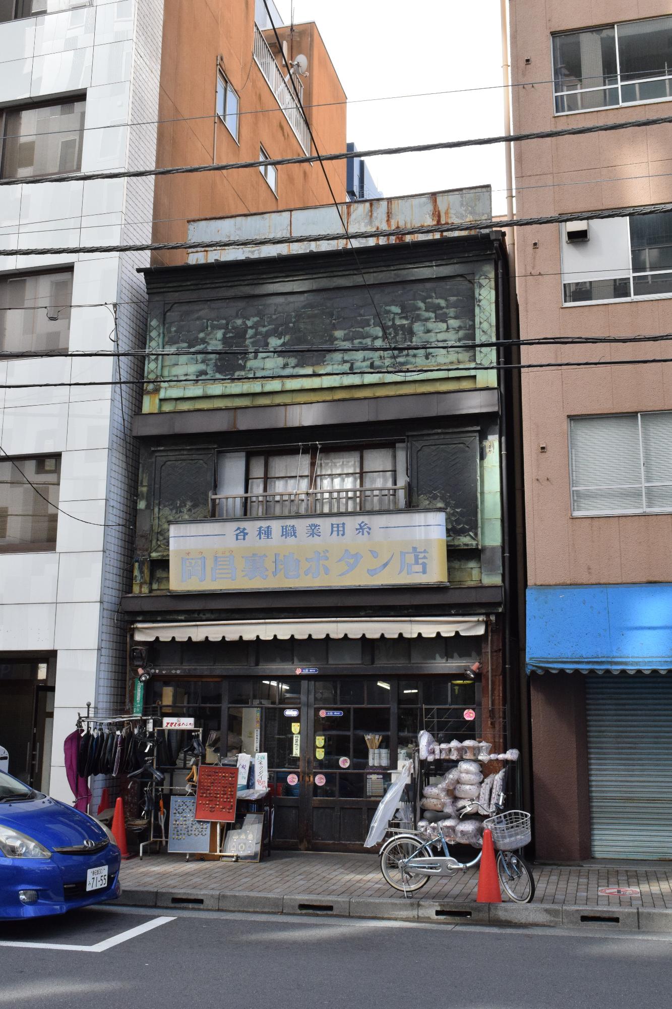 各種職業用糸 岡昌裏地ボタン店の看板が設置された店舗正面を写した写真