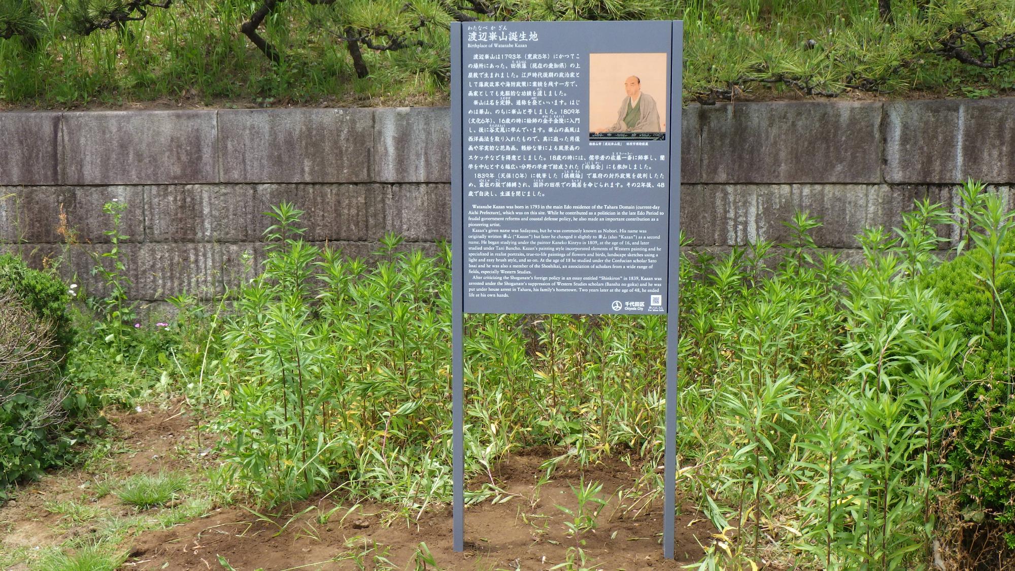 公園内の草むらに設置された渡辺崋山誕生地の説明板の写真