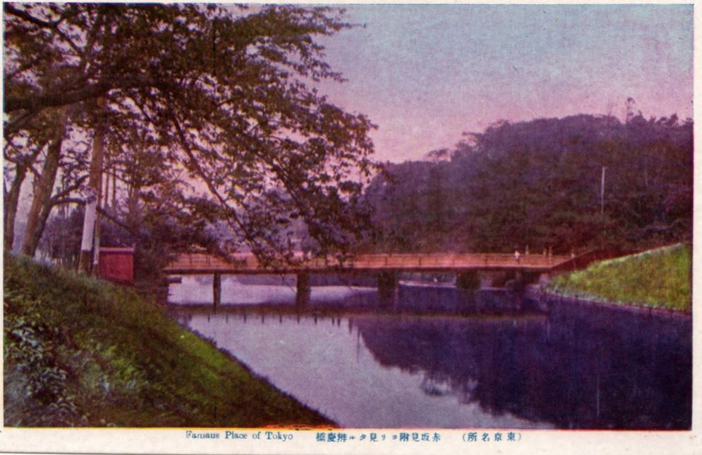 中央の川に弁慶橋が架かり、左の堤防に樹木が植えられている絵葉書を写した写真