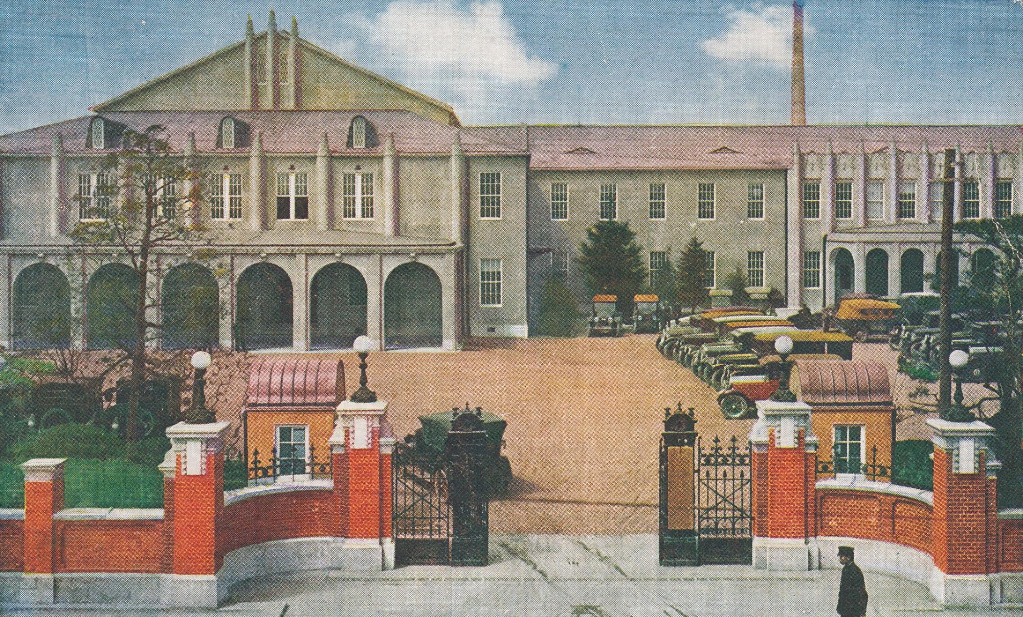 門の両隣に小さな建物が2つあり、駐車場内に車が停車している第三次仮議事堂の建物全体が描かれたイラスト