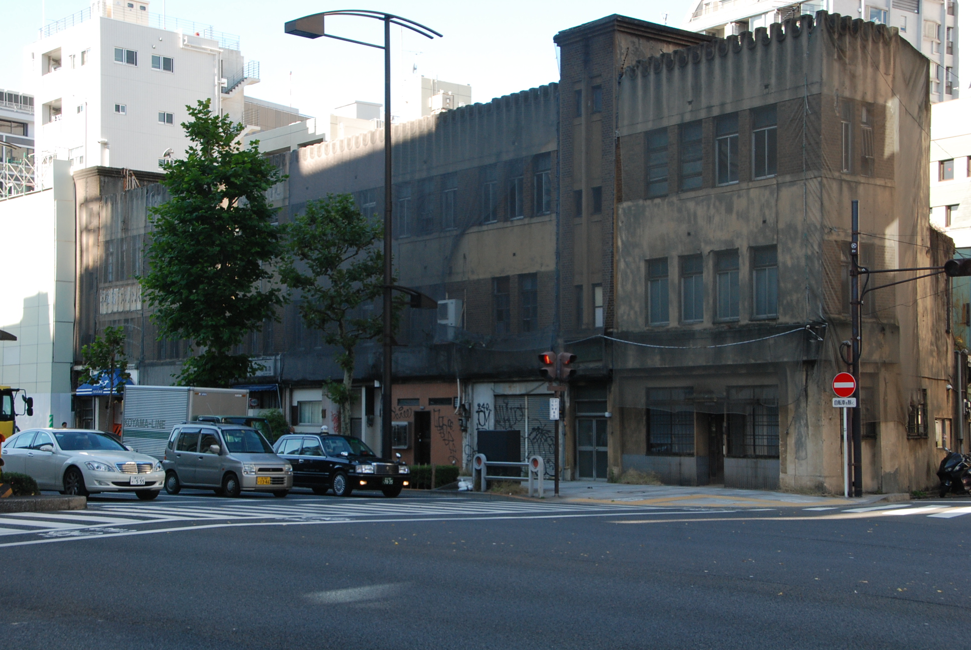 交差点脇に建つ老朽化した3階建て建物の写真