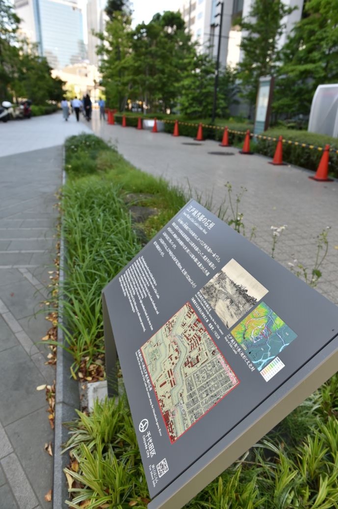 道路沿いの緑道内に設置された江戸城外堀の石垣の説明板の写真