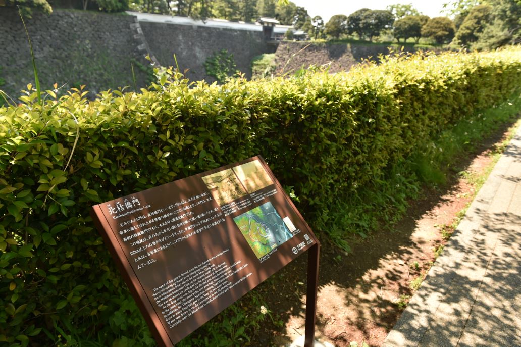 垣根前に北桔橋門の説明板が設置され、陽の光が差している写真