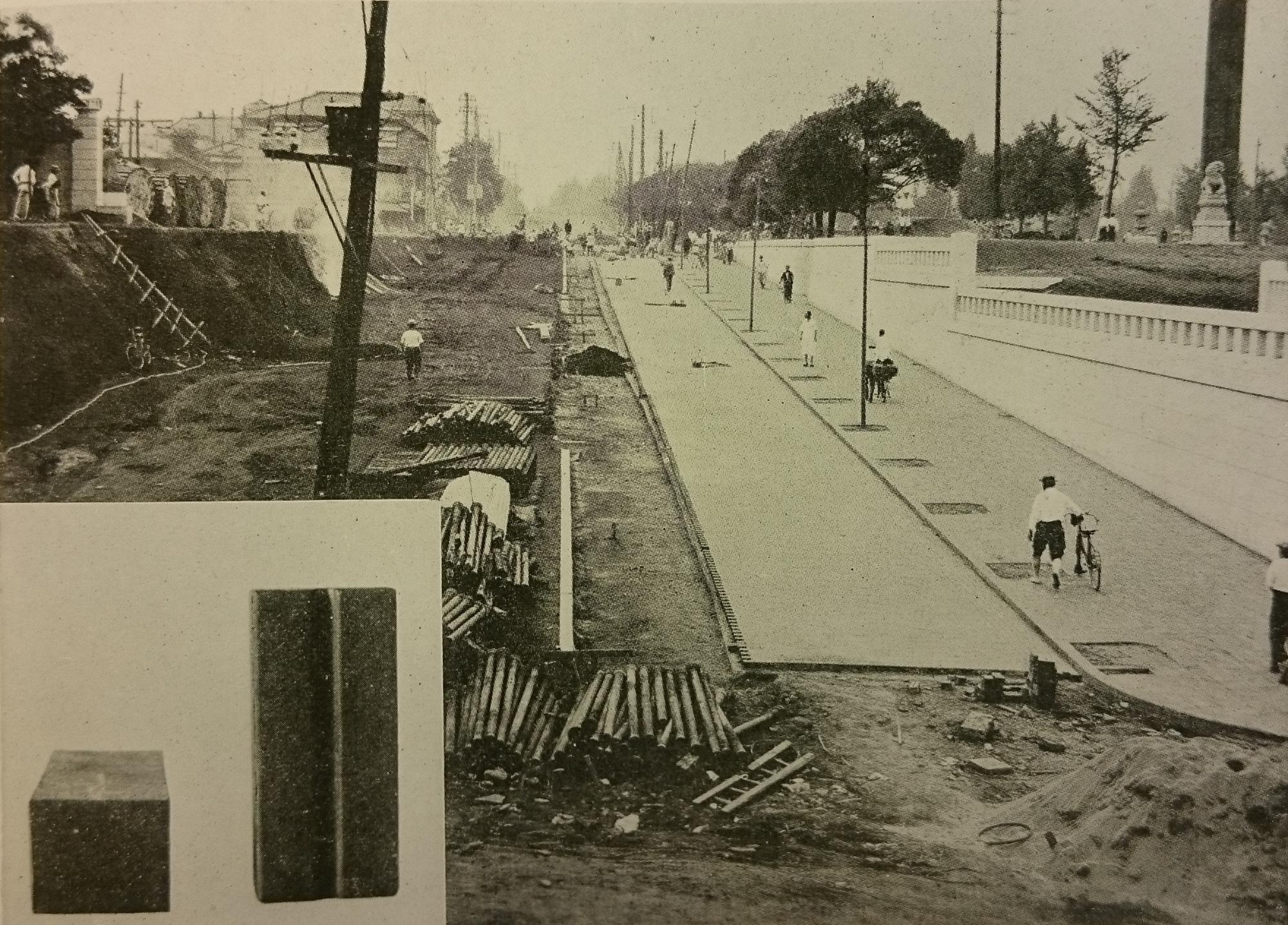 左側の道路の傾斜を緩やかにする工事が行われており、右側を人々が歩いている様子の白黒写真