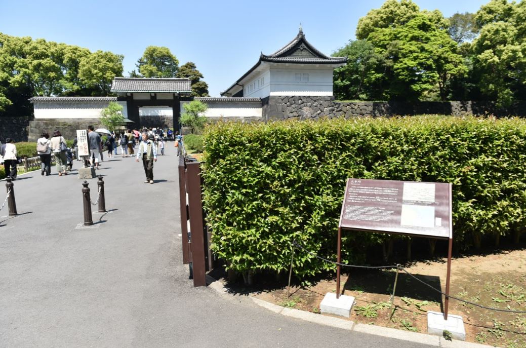 たくさんの人達が大手門橋を歩いていて、その近くにある植栽内に設置された大手門の説明板の写真