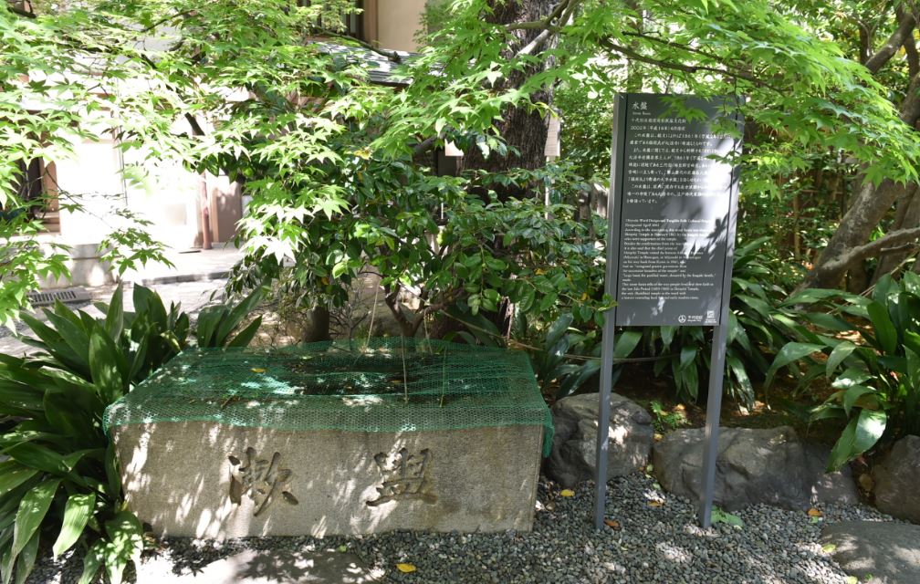 樹木の陰に設置された水盤（心法寺）の説明板の写真
